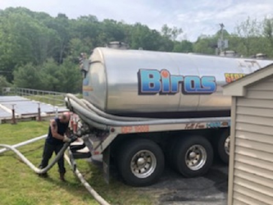 A Biros Septic truck is at a residential location for septic maintenance services.