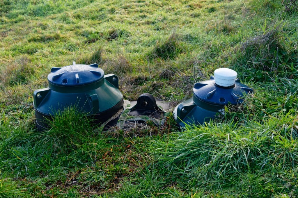 Two septic inspection pipes with overgrown grass around them.