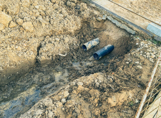sandy ditch with communications. in a new microdistrict of the city, pipes are being laid to bring communications to residential buildings. draining water into the sewer