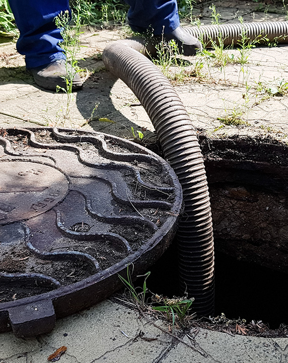 the worker opened the sewer hatch and inserted a hose for cleaning the septic tank. maintenance of communications in a private house