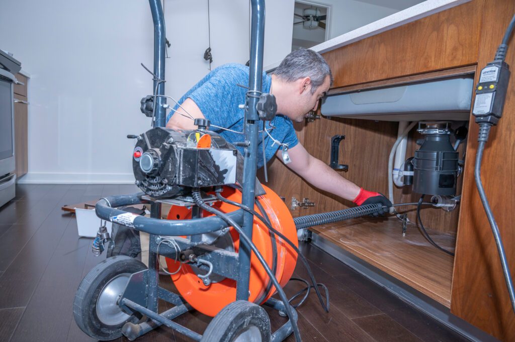 A plumber snakes a clogged drain.