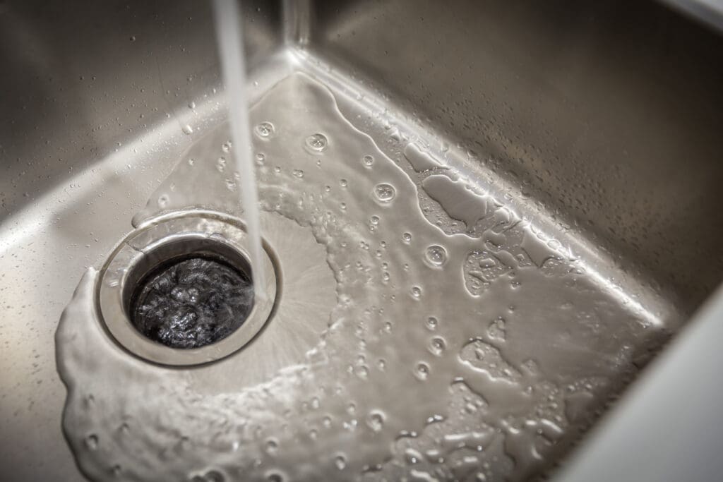 Water flowing from the faucet to the sink drain.