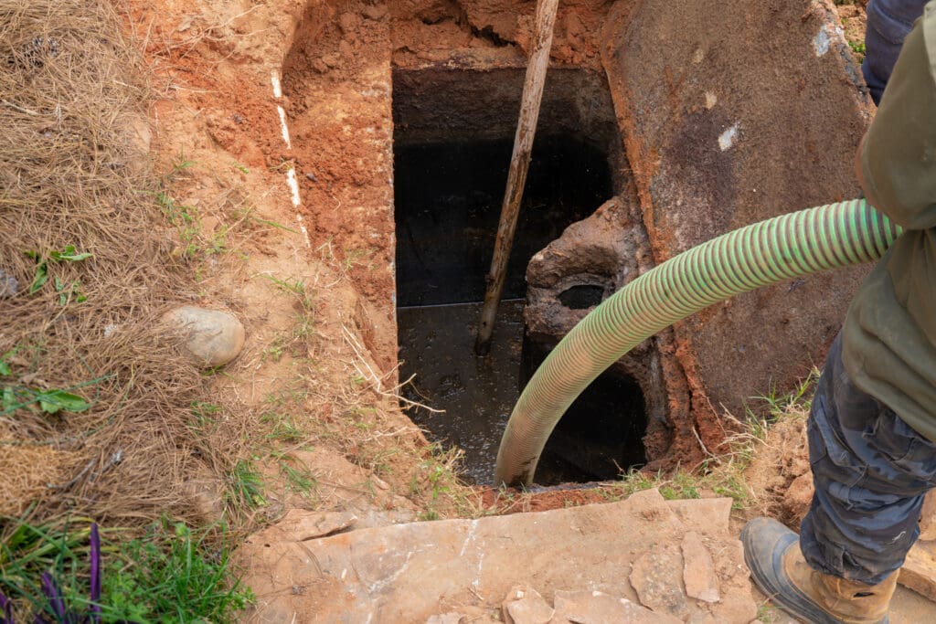 Man holding a hose as he pumps a full septic tank.