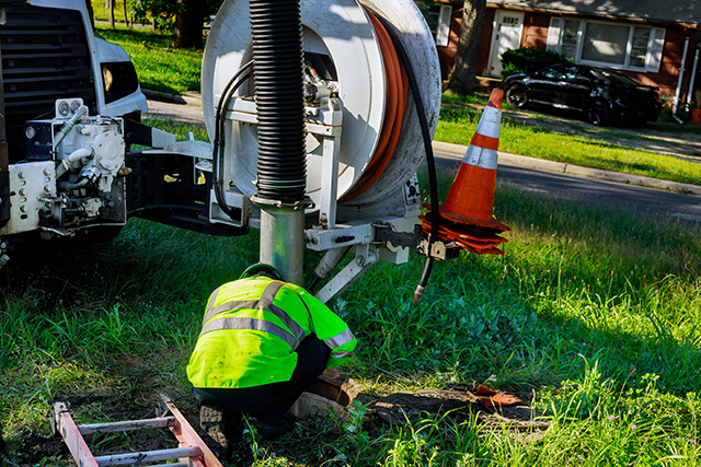 Sewage cleaning workers equipment with sewer on a town street