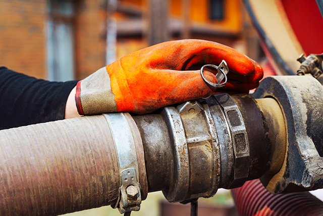 a hand connects a suction hose to a sewage tanker truck. Sewer pumping machine.