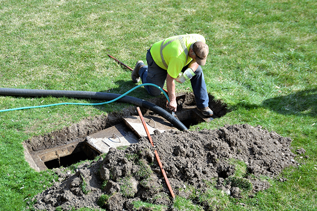 A workman pumping out a backyard septic tank.
