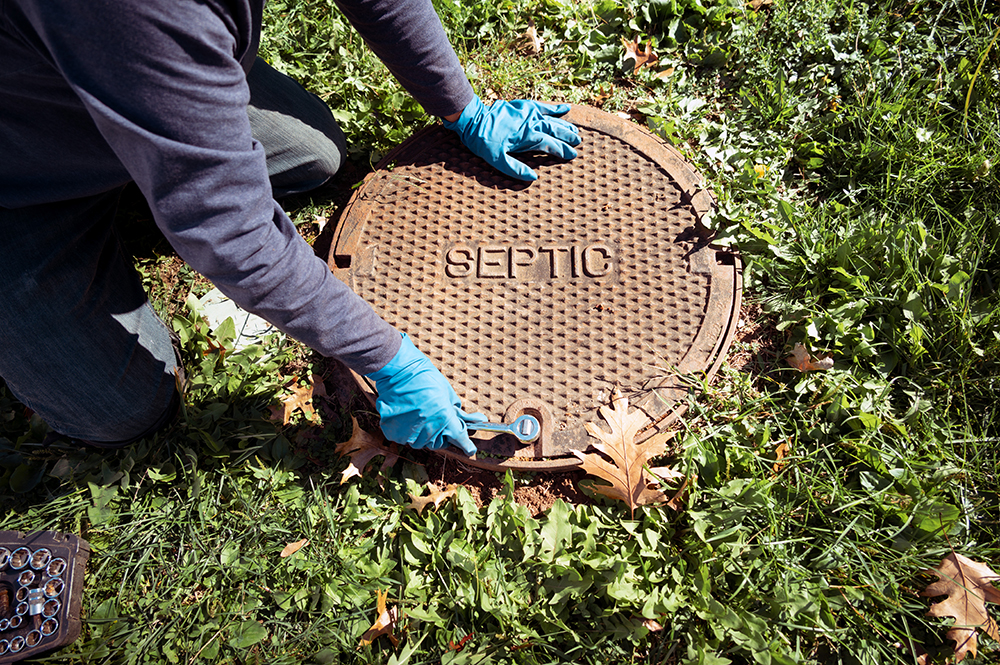 A septic professional opens a septic lid.