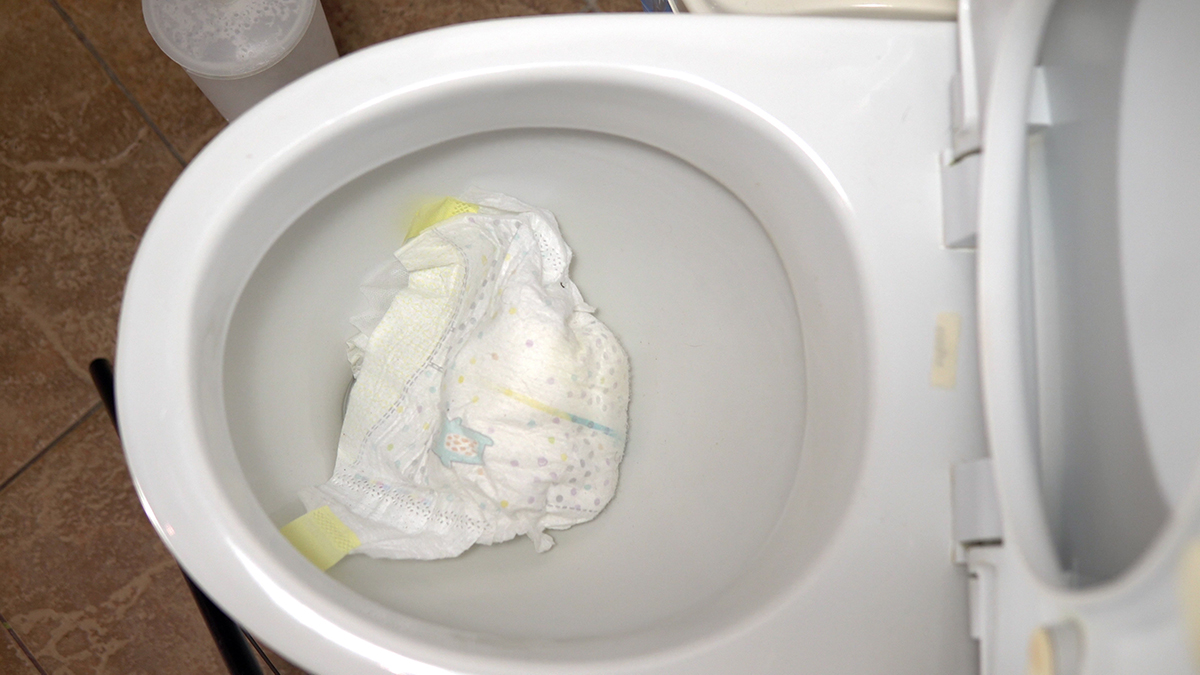A dirty diaper sits at the bottom of a toilet bowl.