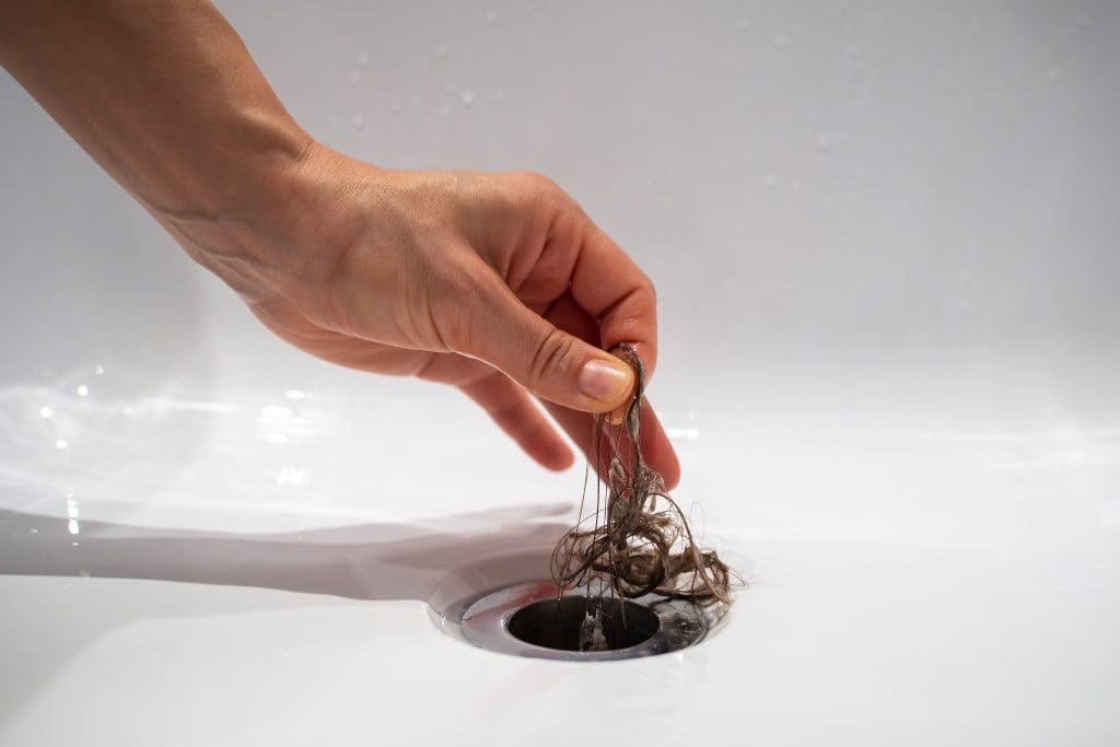 a person pulling hair out of a drain