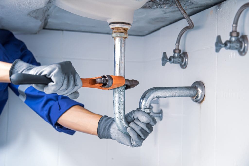 a plumber working on pipes with a wrench