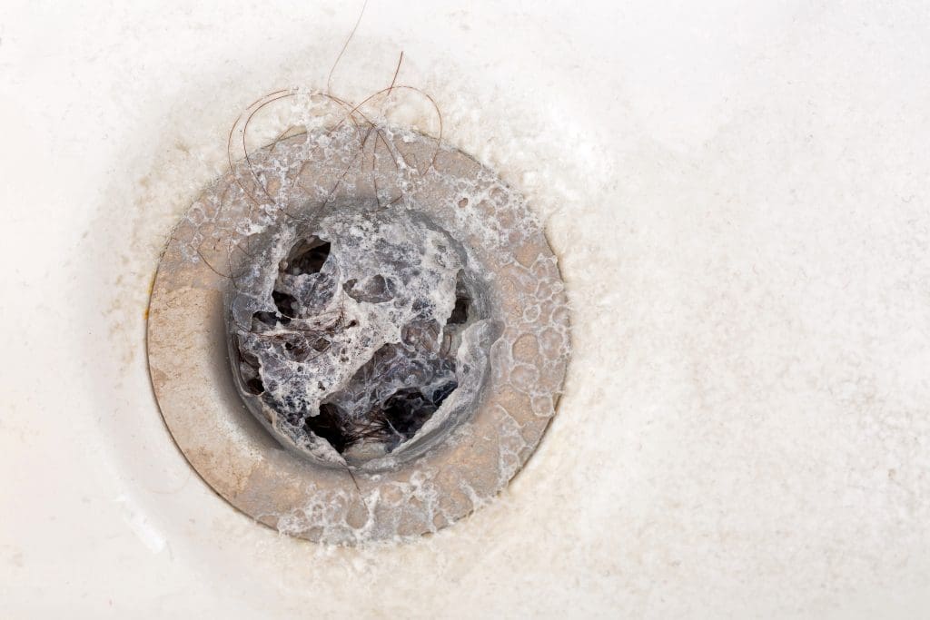 a drain clogged with hair and soap scum
