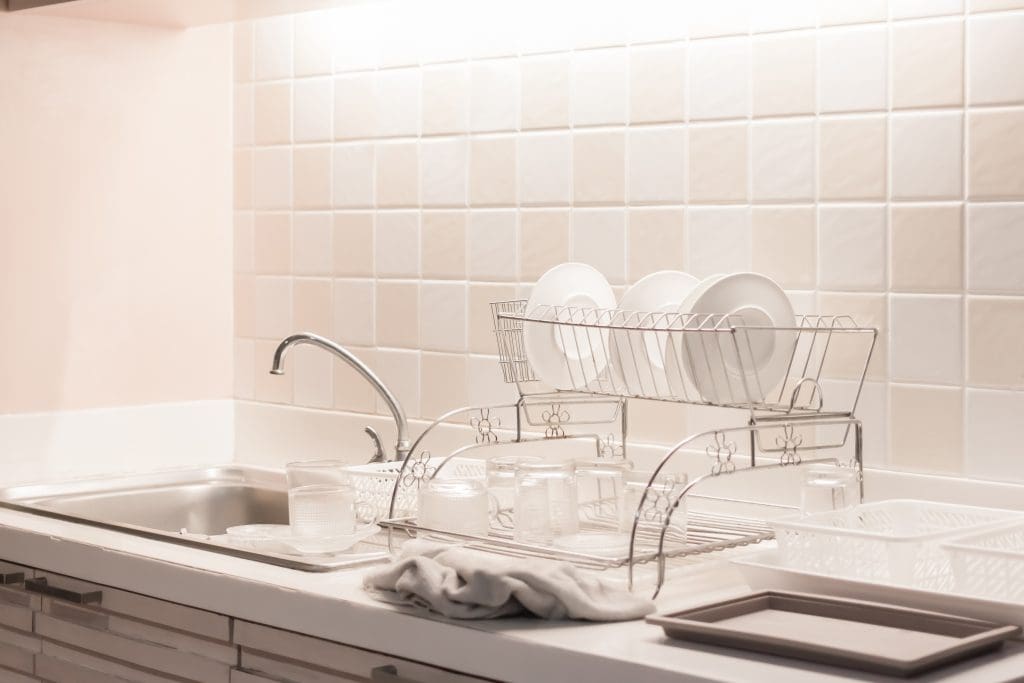 A sink with a dish drying rack to the side of it