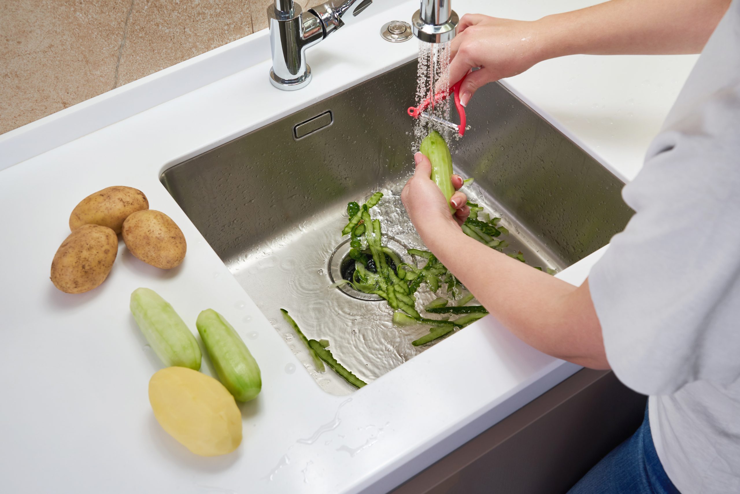 a person peeling vegetables at the sink
