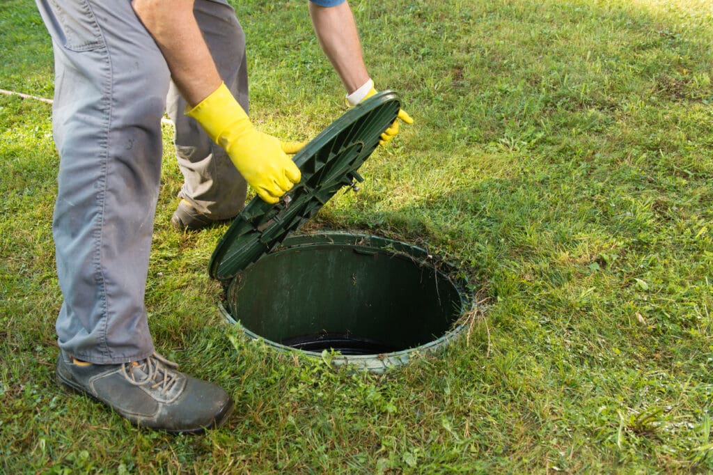 A septic pumping services professional removes a septic tank cover.