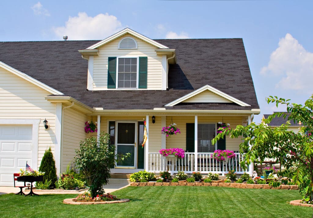 A yellow house with a beautifully manicured yard.