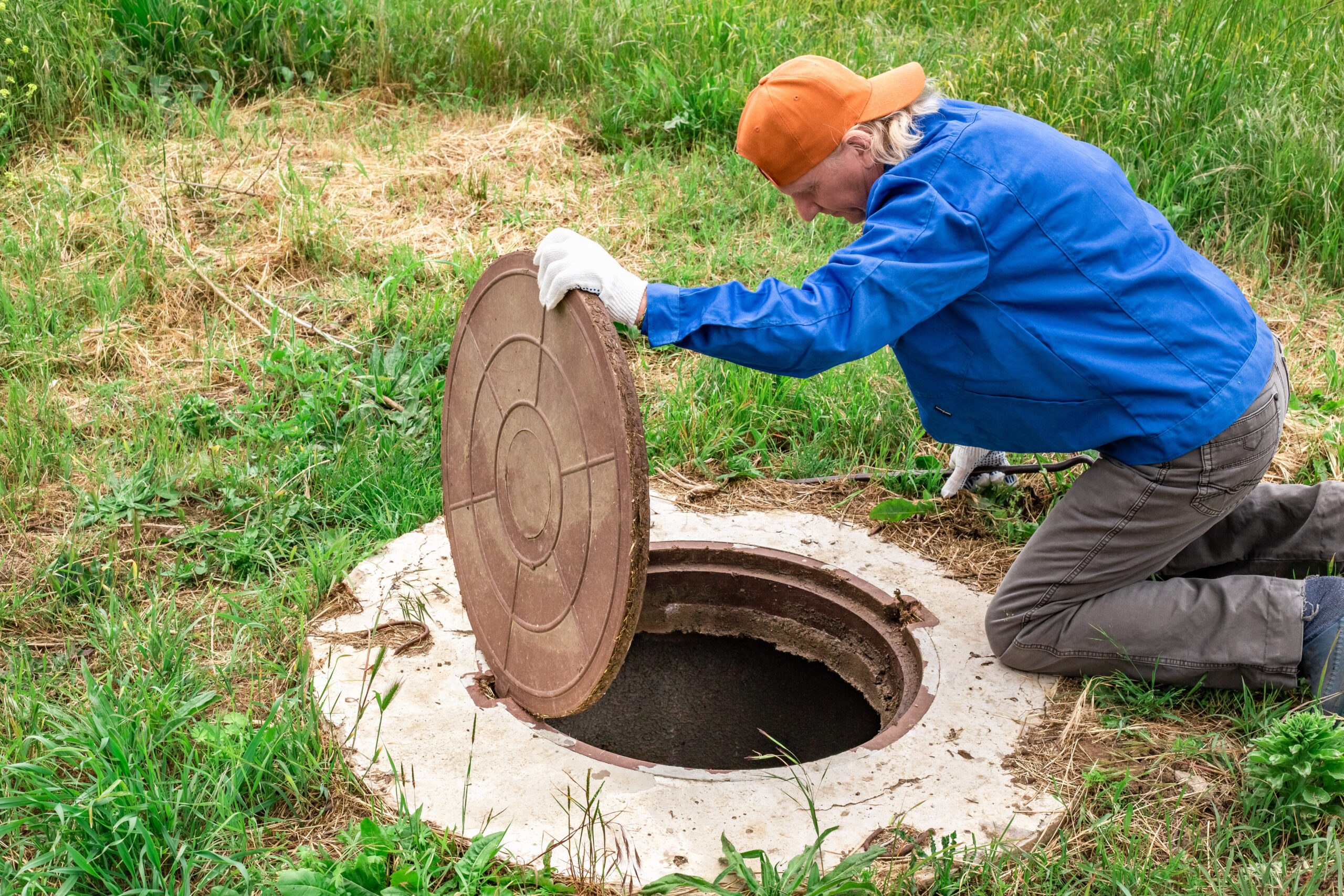 A man looking into a open septic tank.